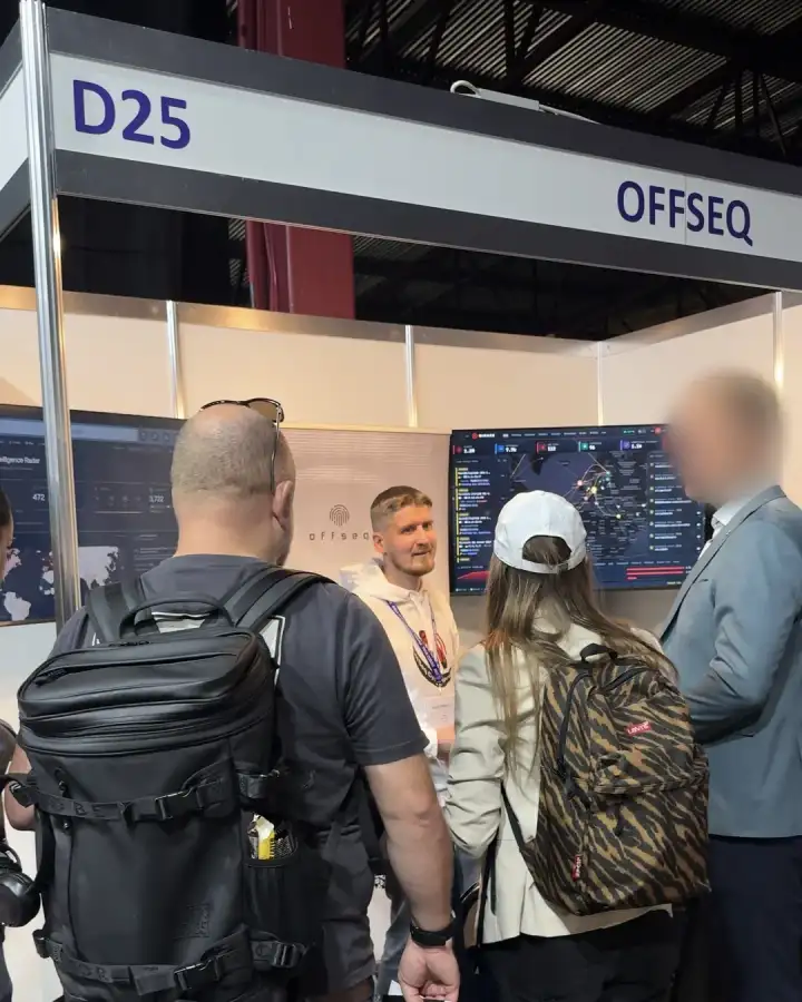 Visitors at the OffSeq stand D25 at RIGA COMM 2026, with live threat dashboards on screen